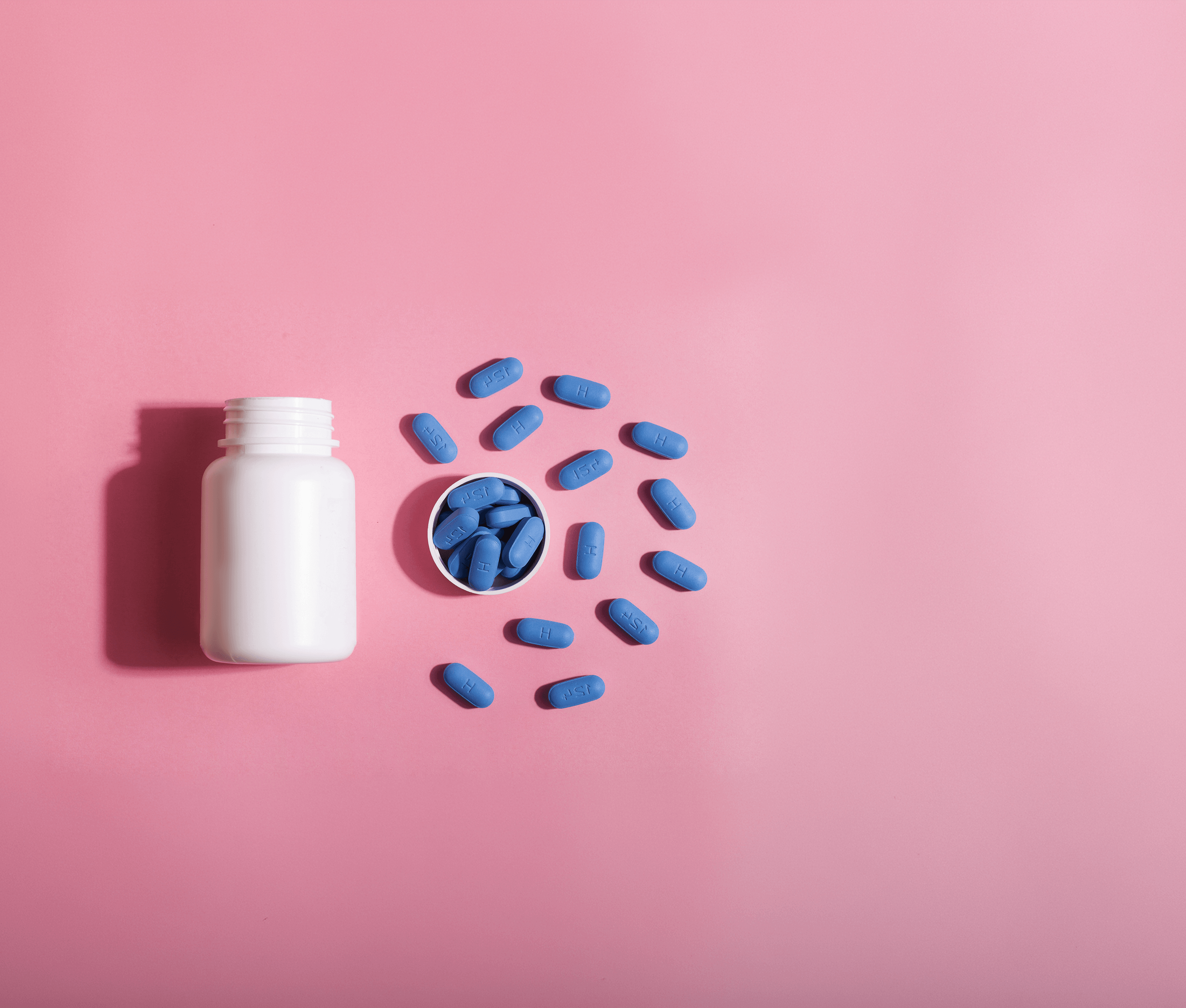 Blue PrEP pills scattered on a pink background