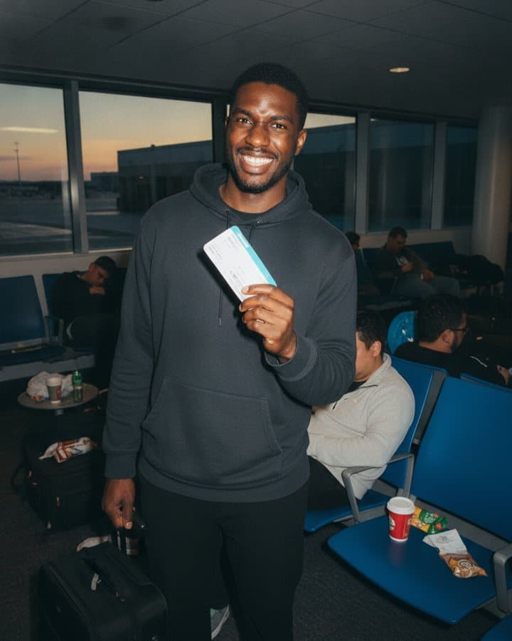 A man at an airport gate holding up a boarding pass